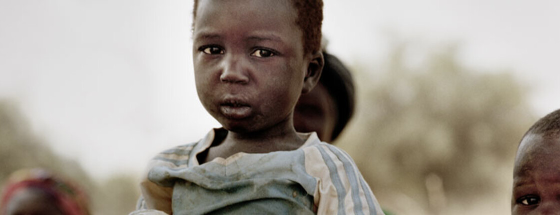 Ein afrikanischer Bub hält einen Wasserbeutel.