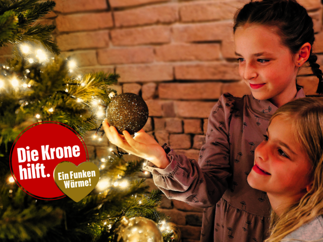 Zwei Mädchen beim Christbaum - und ein Logo "Die Krone hilft. Ein Funken Wärme"