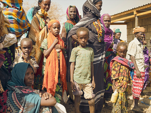 Eine Gruppe afrikanischer Kinder und Erwachsener warten auf die Verteilung von Lebenmitteln.