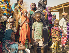 Eine Gruppe afrikanischer Kinder und Erwachsener warten auf die Verteilung von Lebenmitteln.