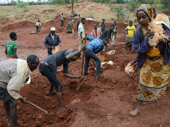 Eine Gruppe von Menschen in Afrika gräbt ein Regenwasser-Sammelbecken.