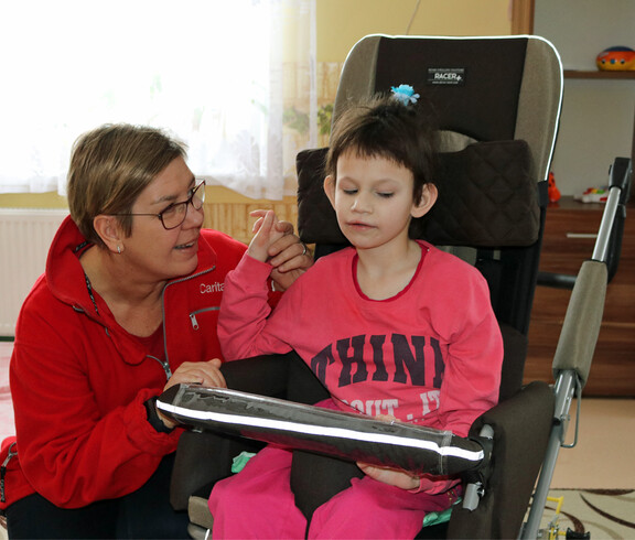 Eine Betreuerin unterstützt ein Kind im Kinderdorf Gomel bei einer therapeutischen Übung und sorgt für eine liebevolle Betreuung.