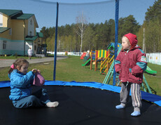 Kinder spielen auf dem Spielplatz im Kinderdorf Gomel, umgeben von Spielgeräten und einer sicheren Umgebung.