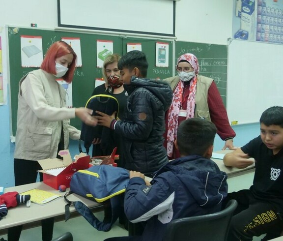 Kinder in einem Klassenraum, mit ihnen sind zwei erwachsene Frauen. 