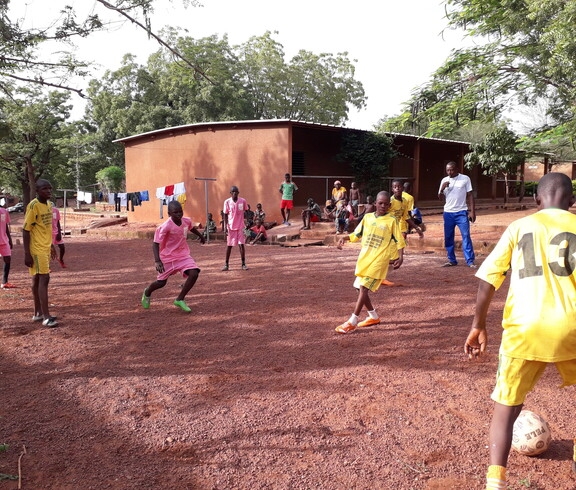 Kinder mit gelben und rosa Trickots spielen Fußball 