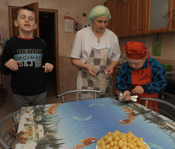 Kinder im Kinderdorf Gomel lernen unter Anleitung einfache Haushaltsaufgaben, wie das ordnungsgemäße Decken des Tisches und den Umgang mit Besteck.