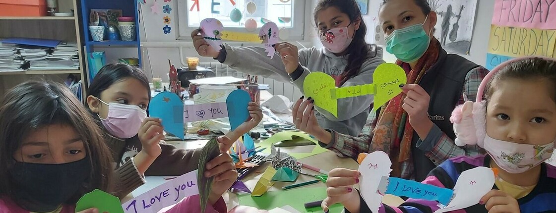 Kinder basteln und halten ihre Basteleien in die Kamera.