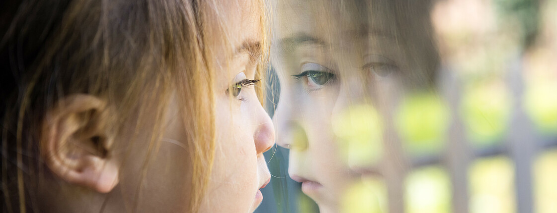 Serious girl looking through a window