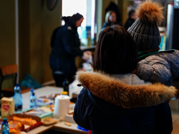 Ukraine-Krieg: Eine Frau mit Kind am Grenzübergang nach Polen, im Hintergrund ist eine Essensausgabe