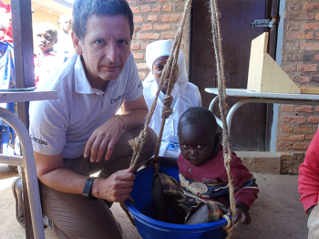 Auslandshilfechef der Caritas Österreich in Burundi mit einem Kind das abgewogen wird. 
